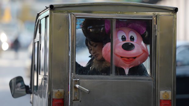 Chinesa em um moto-táxi com balão da personagem Minnie Mouse.  Foi iniciada em Pequim a construção do Shanghai Disney Resort que deverá abrir no final de 2015