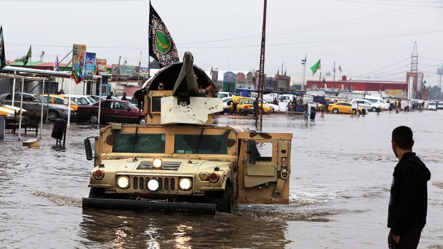 Veículo militar atravessa rua inundada causada por uma sequência de fortes chuvas durante a noite, em Bagdá, no Iraque