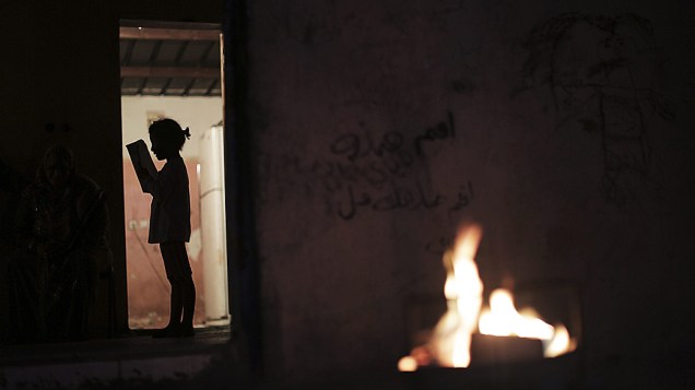 Criança palestina lê à luz de uma fogueira, devido a uma queda de energia na cidade de Beit Lahiya, norte da Faixa de Gaza