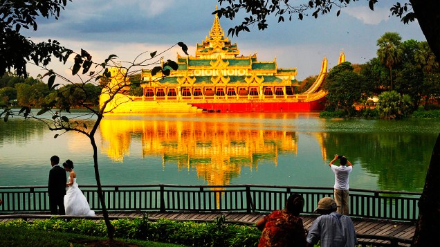 Noivos passam por ponte de madeira no lago Kandawgyi em Yangon, Mianmar Noivos passam por ponte de madeira no lago Kandawgyi em Yangon, Mianmar
