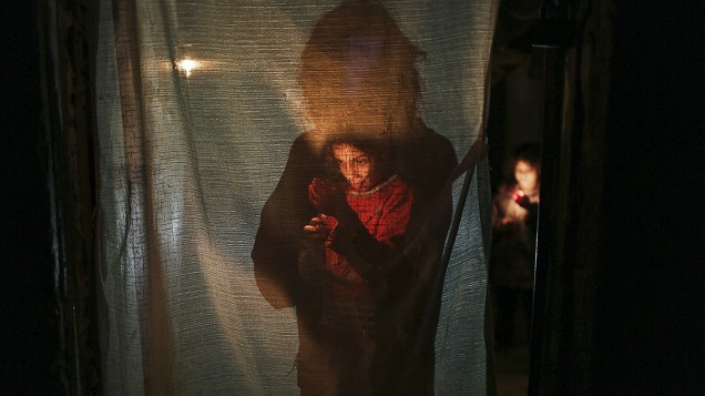 Criança palestina ilumina sua casa com uma vela durante queda de energia na cidade de Beit Lahiya, norte da Faixa de Gaza