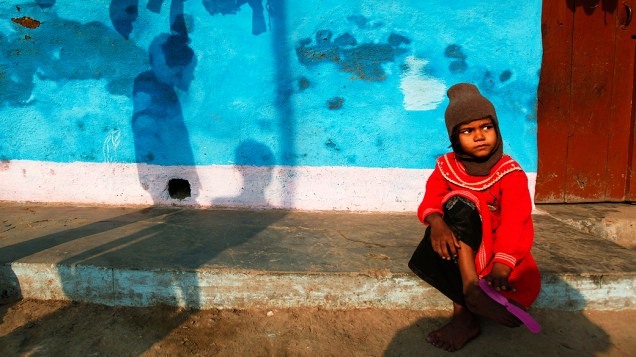 Menina fica do lado de fora de sua casa em uma favela, em Allahabad, na Índia