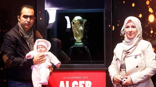 Casal com seu bebê posa ao lado da Taça da Copa do Mundo exibido durante um tour que irá percorrer 88 países em 267 dias, na Argélia