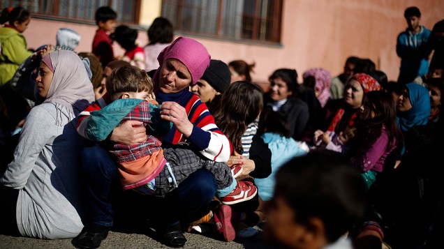 Mulher síria com sua criança senta em uma estrada durante sua visita a um campo de refugiados em Sofia, Bulgária