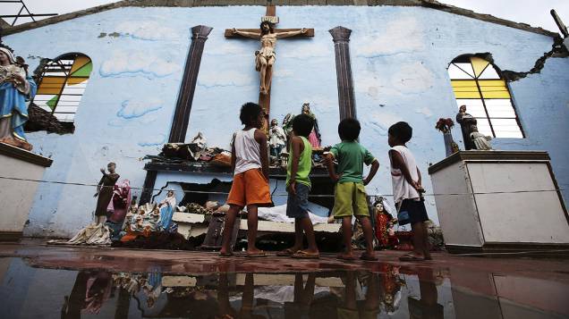 Crianças sobreviventes da passagem do supertufão Haiyan olham para imagens religiosas em uma igreja em ruínas na cidade de Basay, nas Filipinas
