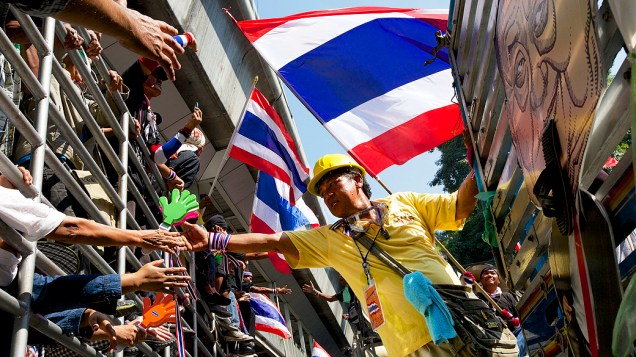 Manifestantes cumprimentam uns aos outros de cima de caminhões durante uma manifestação em frente à sede da polícia central de Bangcoc, na Tailândia. Os manifestantes continuaram seus protestos após vários dias de violentos confrontos com a polícia