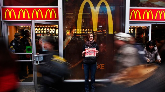 Representante do grupo MoveOn segura um cartaz durante protesto em frente a um restaurante McDonalds na Times Square, em Nova York. O grupo faz uma petição, endereçada às grandes redes de fast food exigindo um salário digno para todos os funcionários do setor