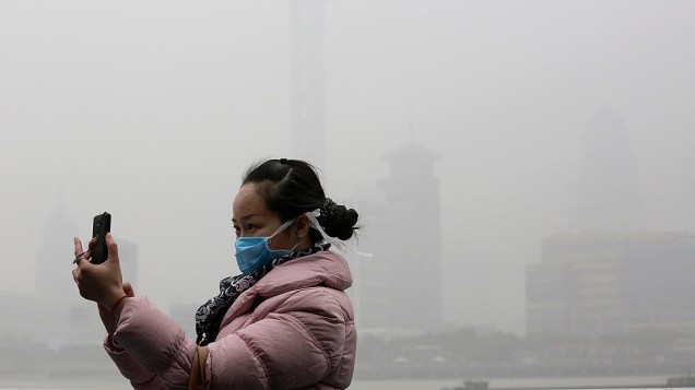 Turista usa máscara de proteção contra névoa de poluição em Xangai, na China, nesta segunda-feira (09)