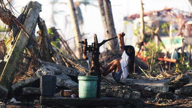 Uma jovem busca água de uma bomba manual na vila Tolosa, Leyte, nas Filipinas. O supertufão Haiyan, que atravessou as Filipinas, deixou milhares de mortos e desabrigados