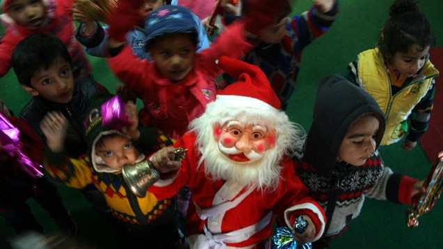 Crianças brincam com Papai Noel em escola, na Índia, nesta segunda-feira (09)