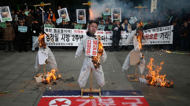 Bonecos do fundador da Coreia do Norte, Kim Il-sung, de Kim Jong-un e de seu pai, Kim Jong-il, são queimados durante um protesto em Seul, Coreia do Sul. As manifestações marcam o segundo aniversário da morte de Kim Jong-il