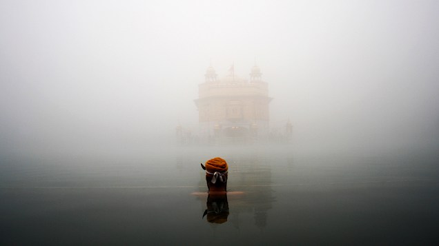 Devoto Sikh se banha em frente ao Templo Dourado em Amritsar, na Índia