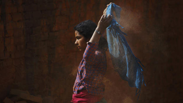 Menina sacode lenço durante trabalho em uma fábrica de tijolos em Lalitpur, na Índia