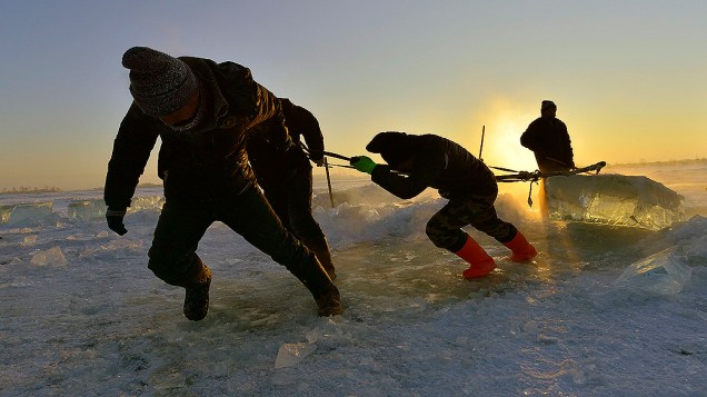 Trabalhadores puxam um cubo de gelo gigante retirado do rio Songhua para montagem das esculturas que serão expostas durante o Harbin Ice and Snow Festival, em Harbin, província de Heilongjiang, na China