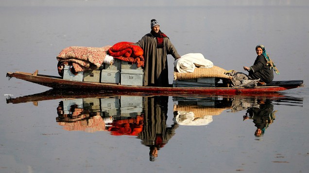 Homem transporta seus pertences em uma canoa após ter sua casa destruída por um incêndio em Dhobi Ghat, nos arredores de Srinagar, na região da Caxemira administrada pela Índia