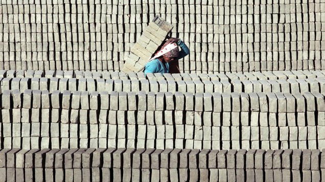 Mulher carrega uma pilha de tijolos durante o dia de trabalho em Lalitpur, Nepal