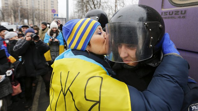 Manifestante pró União Europeia beija o capacete de um policial durante protesto em Kiev