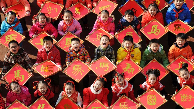 Crianças seguram cartazes de papel com o caractere cavalo do zodíaco chinês, em uma escola primária em Jiujiang na China