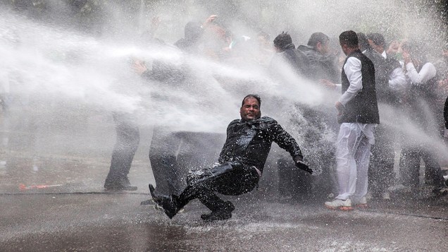 Ativista do partido de oposição indiano Bharatiya Janata atingido por um jato de água disparado pela polícia durante um protesto em frente a residência do vice-presidente do Congresso, Rahul Gandhi, em Nova Délhi