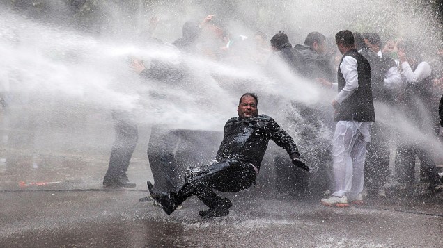 Ativista do partido de oposição indiano Bharatiya Janata é atingido por jato de água disparado pela polícia durante um protesto em frente a residência do vice-presidente do Congresso, Rahul Gandhi, em Nova Délhi Ativista do partido de oposição indiano Bharatiya Janata é atingido por jato de água disparado pela polícia durante um protesto em frente a residência do vice-presidente do Congresso, Rahul Gandhi, em Nova Délhi