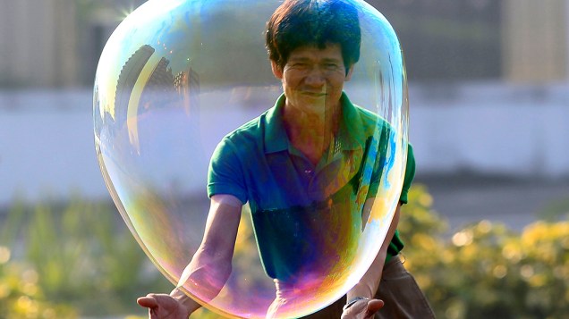 Um homem brinca com uma bolha ao comemorar o dia de Ano Novo em um parque em Manila, nas Filipinas