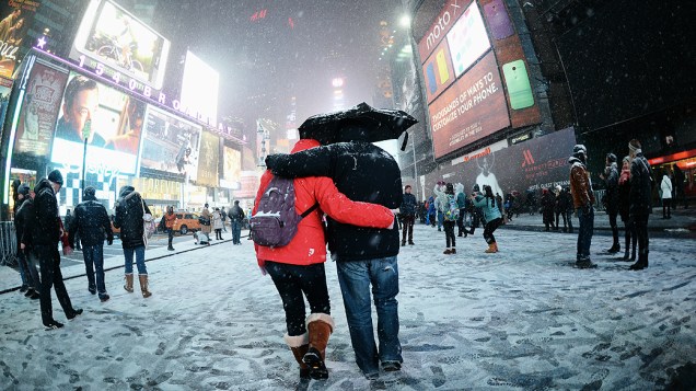 Casal caminha pela a Broadway coberta de neve na Times Square, em Nova York