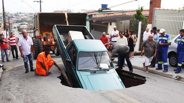 Carro cai dentro de uma cratera que se abriu na Rua Pernambuco, em Itapecerica da Serra, SP, na manhã desta quinta-feira (02)