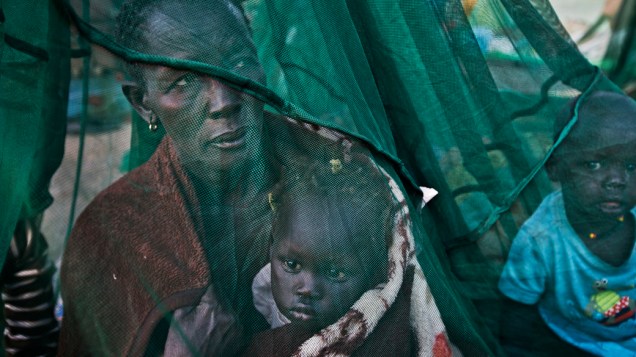 Família refugiada do recente conflito entre o governo e as forças rebeldes se abriga sob um mosqueteiro na cidade de Awerial, no Sudão do Sul nesta quinta-feira (02)