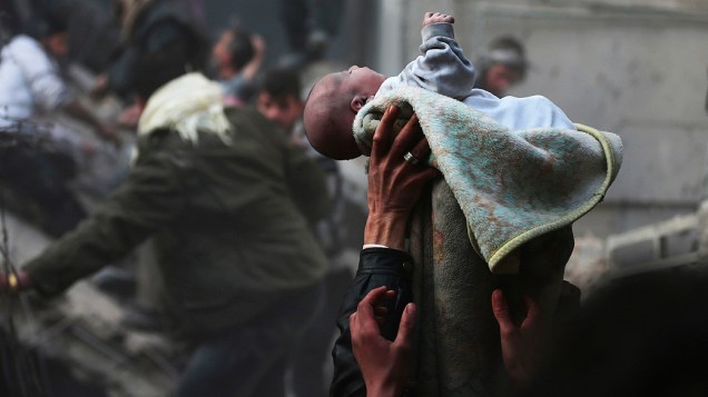 Na Síria, bebê é resgatado com vida de escombros após ataque aéreo ao distrito de Duma, em Damasco