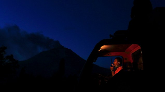 Membro da equipe de busca e salvamento usa seu walkie talkie dentro de um caminhão enquanto Monte Sinabung expele cinzas na vila do distrito de Karo Berastepu, na Indonésia