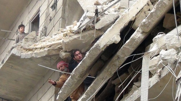 Sírios em um prédio após ataque aéreo no norte da cidade de Aleppo