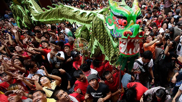Pessoas tentam pegar envelopes com dinheiro e outros itens que são jogados enquanto seguem o dragão, durante a celebração do Ano Novo chinês, em um bairro chinês das Filipinas