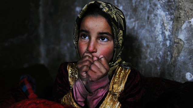 Menina afegã se aquece durante forte nevasca em Erat, no Afeganistão, nesta sexta-feira (07)