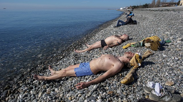 Moradores tomam sol em uma praia do Mar Negro perto do Estádio Olímpico de Sochi, na Rússia