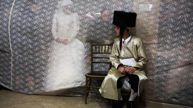 Noiva judia olha para seu noivo atrás de uma cortina durante o ritual de dança (Mitzvah Tans) após o seu casamento em um bairro ultra-ortodoxo de Jerusalém