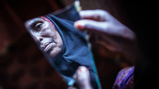 Amran Mahamood, que fez a vida por 15 anos por circuncidando meninas, olha para um pedaço de um espelho, em Hargeisa, na Somália