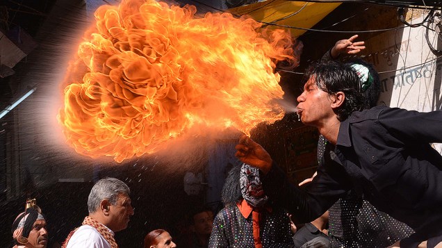 Devoto hindu cospe fogo em uma procissão durante o festival Holi em Amritsar, na Índia