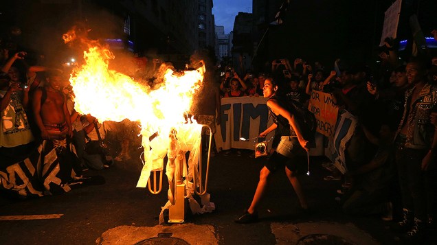 Manifestantes dançam em torno de uma catraca incendiada no centro do Rio de Janeiro, para protestar contra o aumento da tarifa de ônibus, que entrou em vigor no último sábado (08)