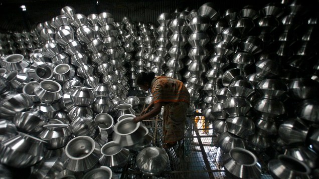 Em Agartala, indiana arruma utensílios em fábrica de alumínio