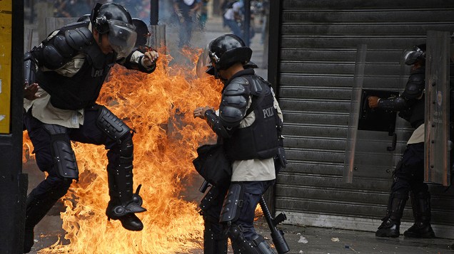 Polciais se protegem de um coquetel Molotov atirado por um manifestante em Caracas. Os protestos na Venezuela se arrastam desde fevereiro, e já deixou 41 pessoas mortas e cerca de 600 feridos