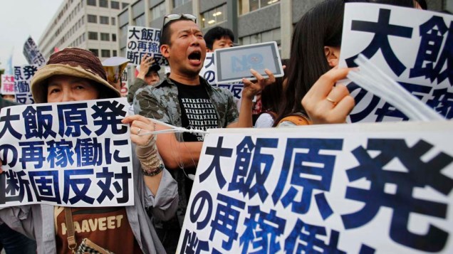 Manifestantes segurar cartazes dizendo: "Contra o reinício da usina nuclear de Ohi" em frente a residência oficial do primeiro-ministro japonês, em Tóquio