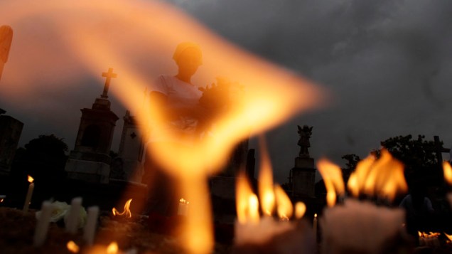 Mulher acende velas no dia de Finados, no Rio de Janeiro