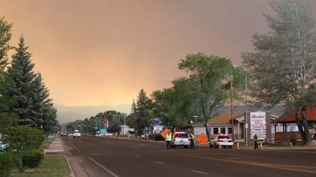 Policiais bloqueiam estrada a caminho de Eagar, Arizona. O incêndio que atingiu a região destruiu parte da floresta local e cerca de 2.000 moradores foram evacuados do local