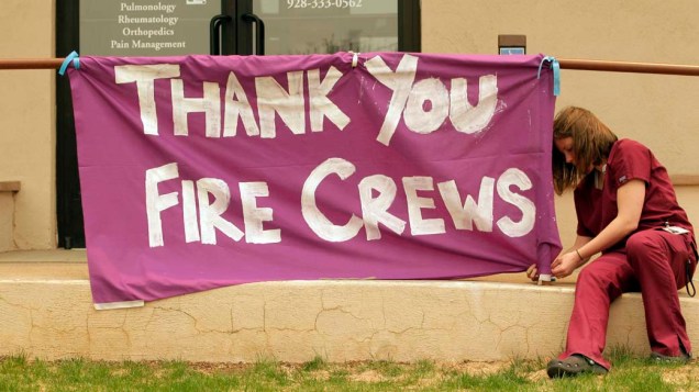 Funcionária de um hospital amarra cartaz em agradecimento aos bombeiros na cidade de Springerville, Arizona
