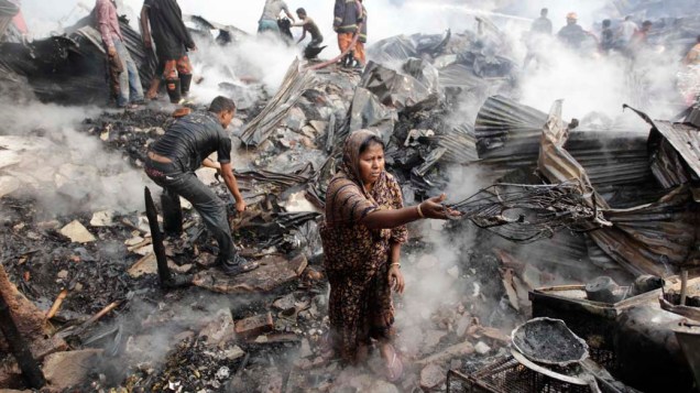 Mulher tenta recuperar pertences após incêndio em favela na cidade de Dhaka, em Bangladesh