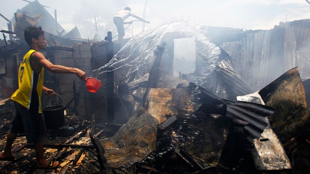 Voluntários tentam apagar incêndio em uma colônia de posseiros em Makati City (Manila). O fogo destruiu pelo menos 200 casas de lata