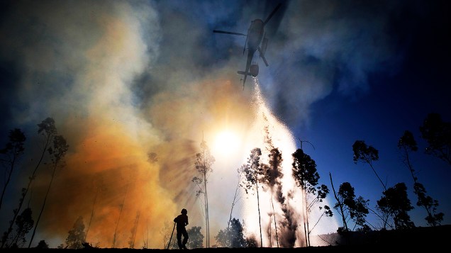 Helicóptero despeja água sobre vegetação em chamas em Alvaiazere, perto de Ourem, em Portugal. Uma pessoa morreu e três ficaram feridas. O governo português solicitou a outros países europeus que enviem ajuda para extinguir o incêndio