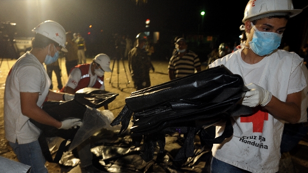 Após incêndio em prisão hondurenha, paramédicos carregam sacos de plástico para remoção de cadáveres