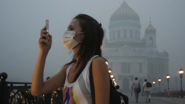 Garota usa máscara para se proteger contra a fumaça em Moscou