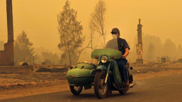 Munido de máscara, russo dirige motocicleta no vilarejo russo de Kriusha, um dos atingidos pelos incêndios